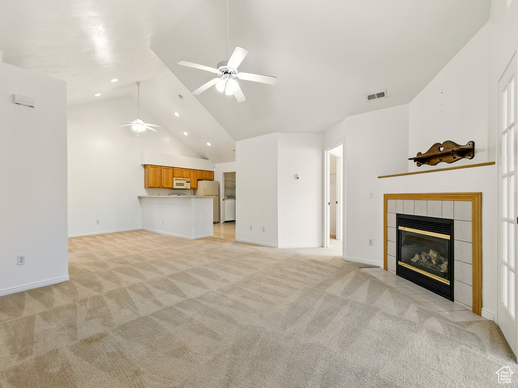 Unfurnished living room with ceiling fan, light colored carpet, a fireplace, high vaulted ceiling, and recessed lighting