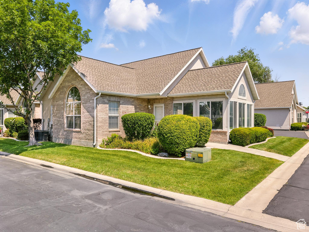 View of front facade featuring roof with shingles, a front yard, and brick siding