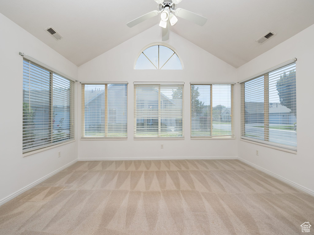Unfurnished sunroom with carpet, vaulted ceiling, and plenty of natural light