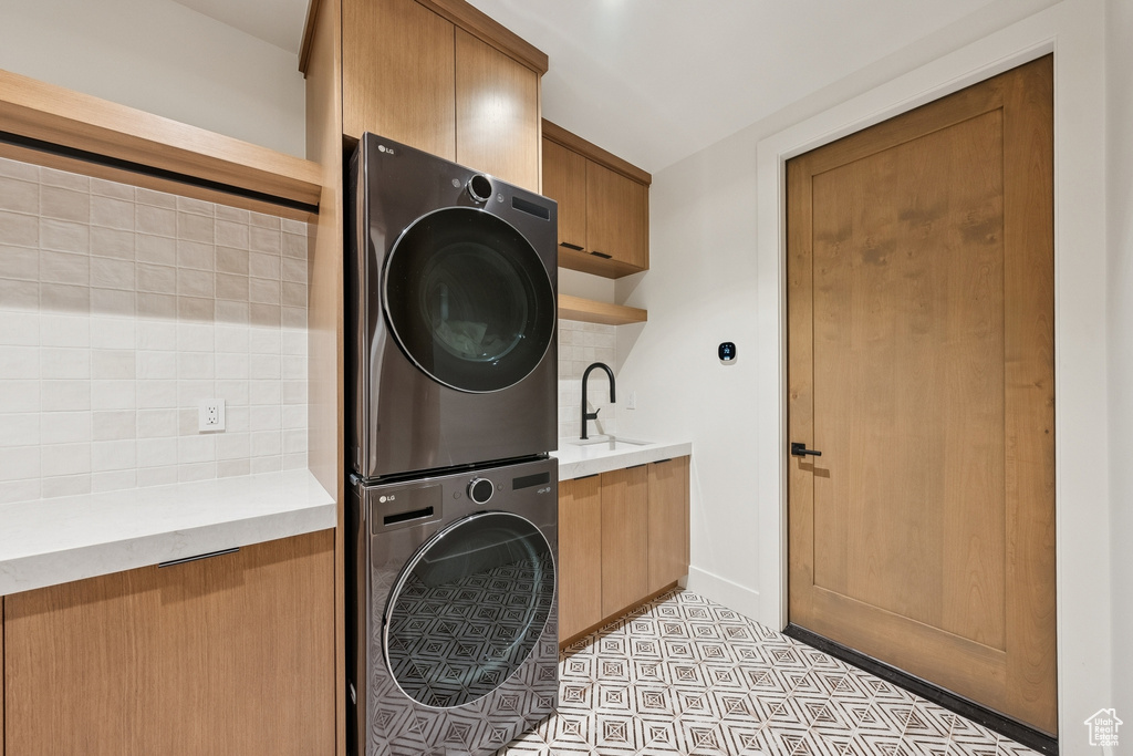 Laundry area featuring stacked washer / dryer and cabinet space