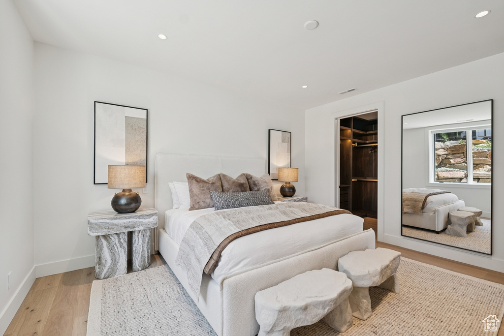 Bedroom with light wood finished floors, recessed lighting, a walk in closet, and a closet