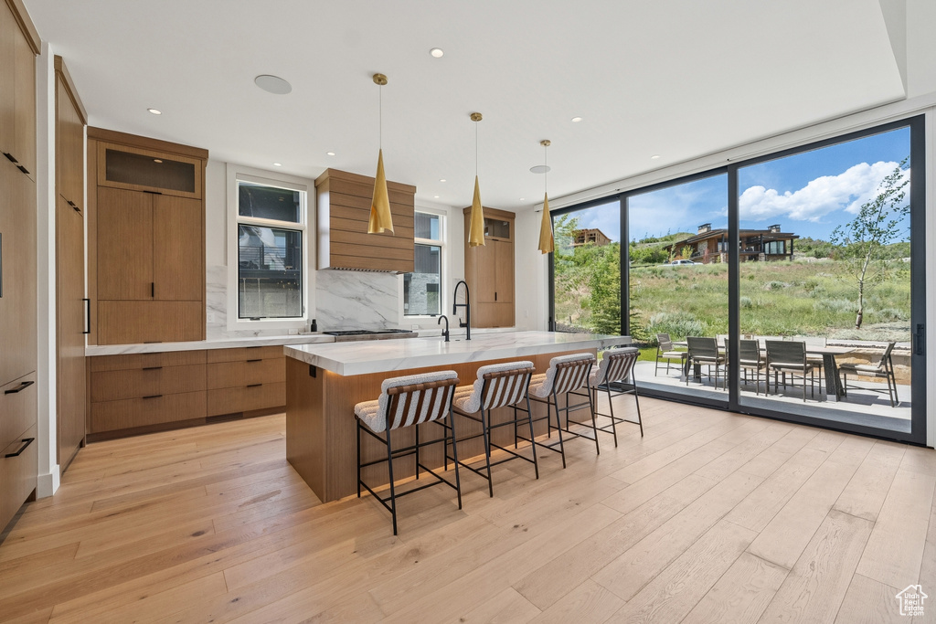 Kitchen with modern cabinets, brown cabinetry, light countertops, a large island, and floor to ceiling windows