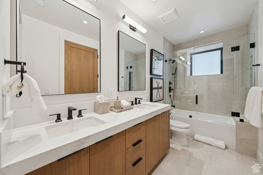Full bathroom with double vanity, combined bath / shower with glass door, and recessed lighting