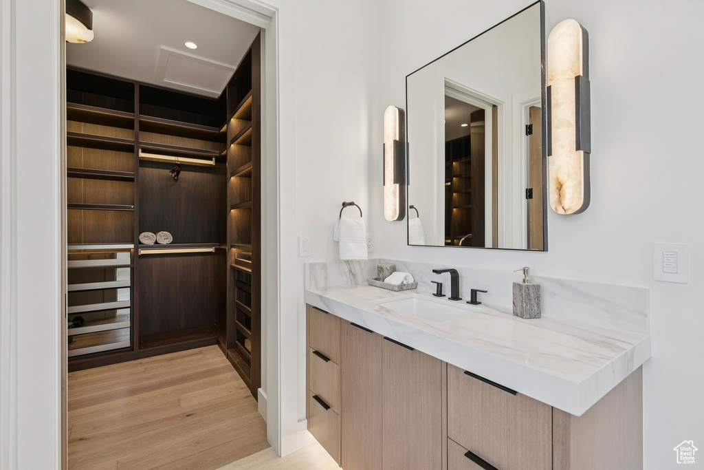 Bathroom featuring vanity, wood finished floors, and a walk in closet