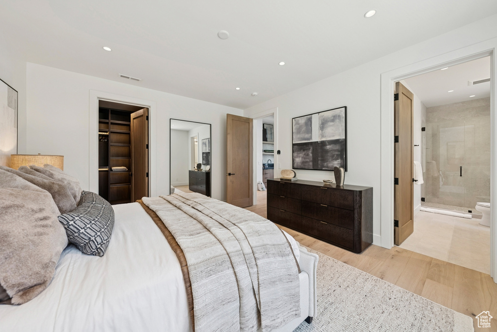 Bedroom featuring light wood-type flooring, recessed lighting, a spacious closet, ensuite bath, and a closet