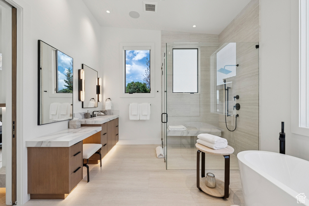 Bathroom featuring a stall shower, vanity, and a soaking tub
