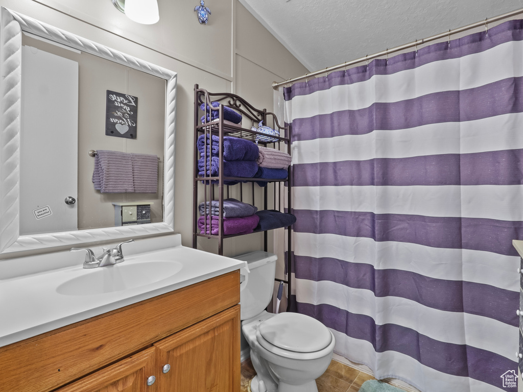 Full bath featuring toilet, vanity, a textured ceiling, a shower with curtain, and tile patterned floors