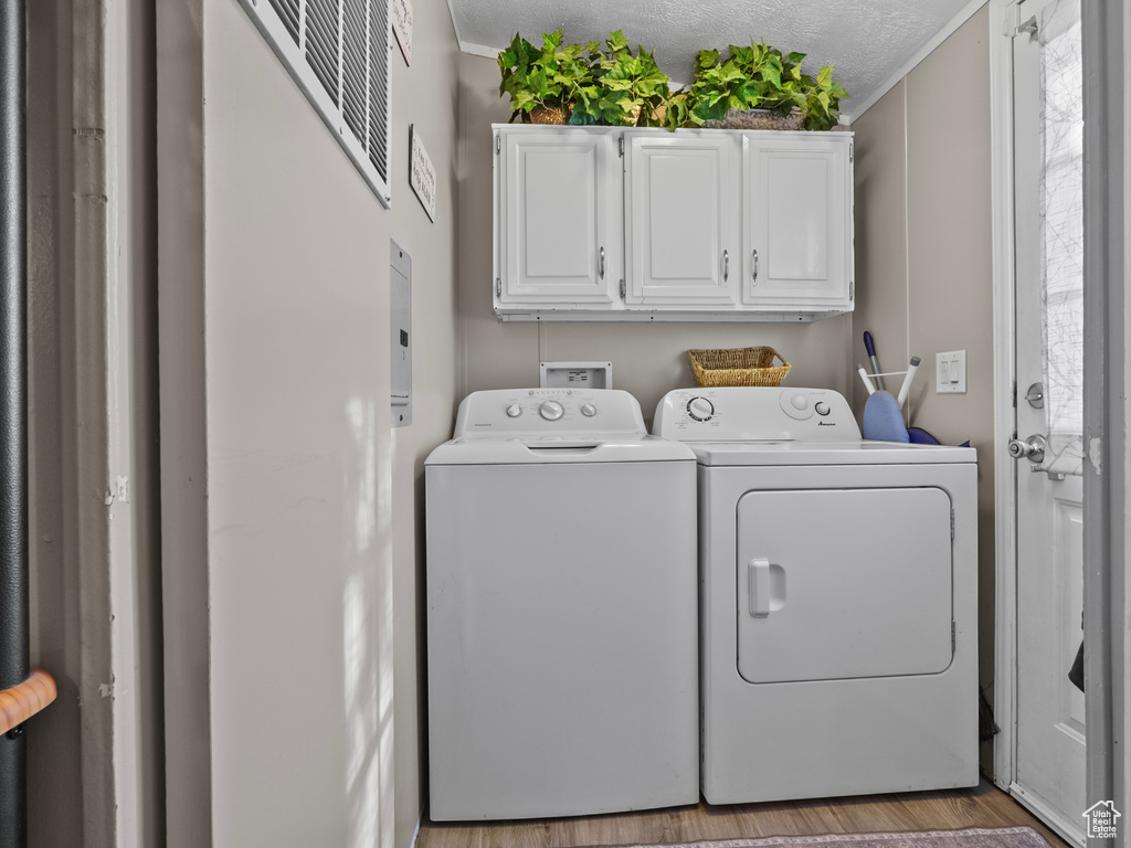 Laundry area featuring cabinet space, washing machine and clothes dryer, and wood finished floors
