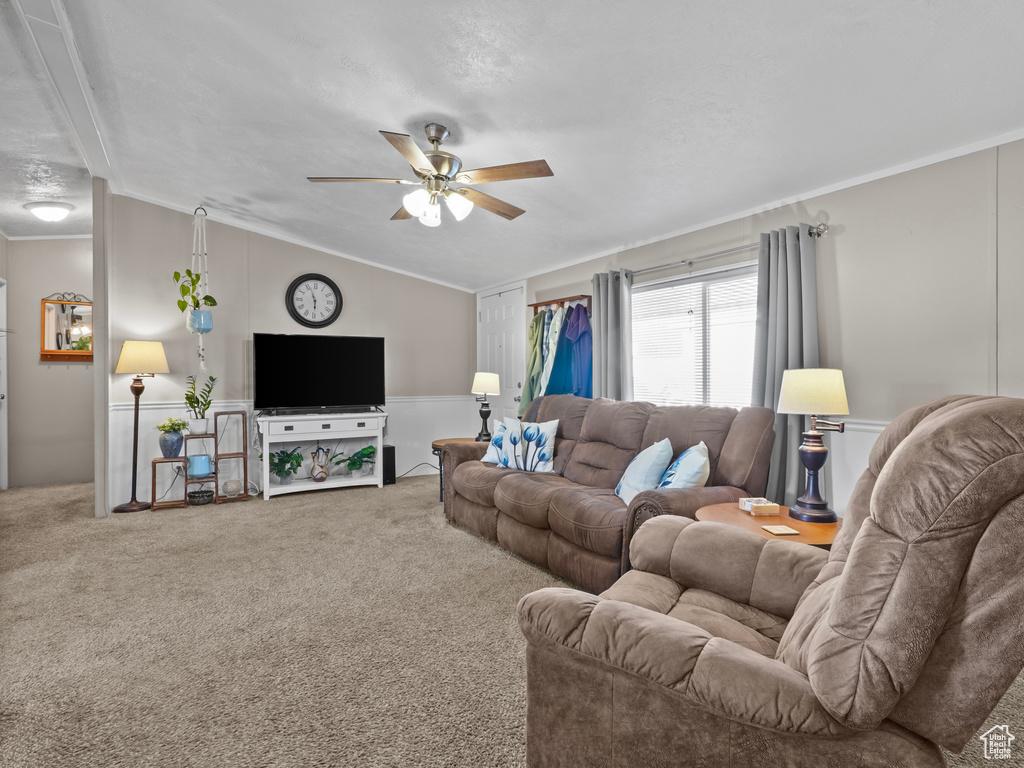 Living area with ornamental molding, carpet flooring, ceiling fan, and vaulted ceiling