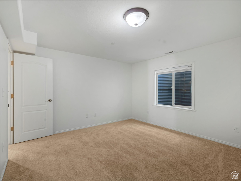 Carpeted spare room featuring baseboards