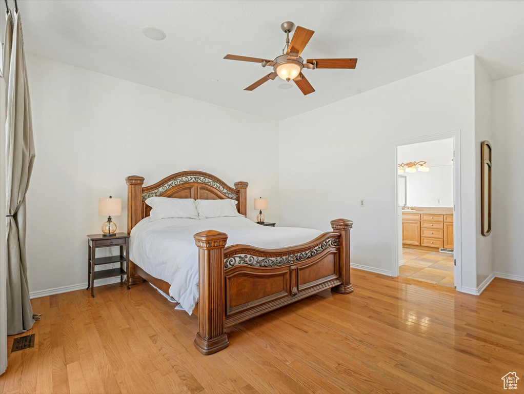 Bedroom with light wood finished floors, ensuite bathroom, and a ceiling fan