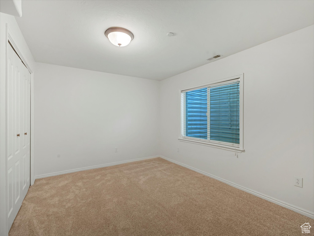 Unfurnished bedroom featuring light colored carpet and a closet