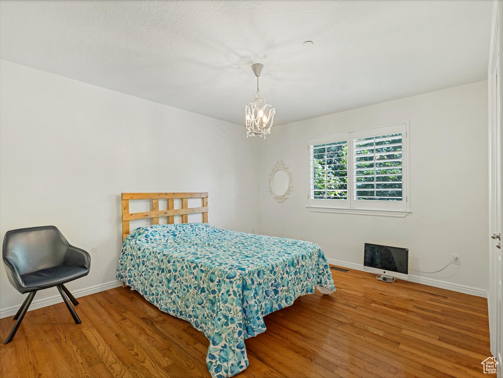 Bedroom featuring wood finished floors and a chandelier