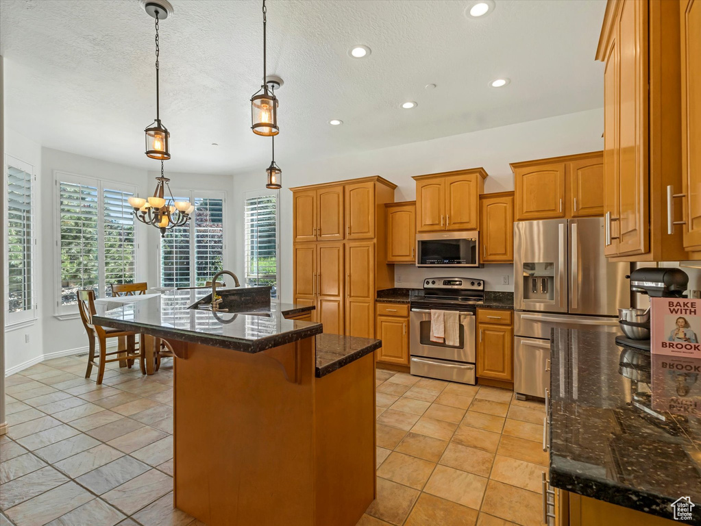 Kitchen featuring appliances with stainless steel finishes, recessed lighting, a chandelier, a kitchen breakfast bar, and brown cabinetry