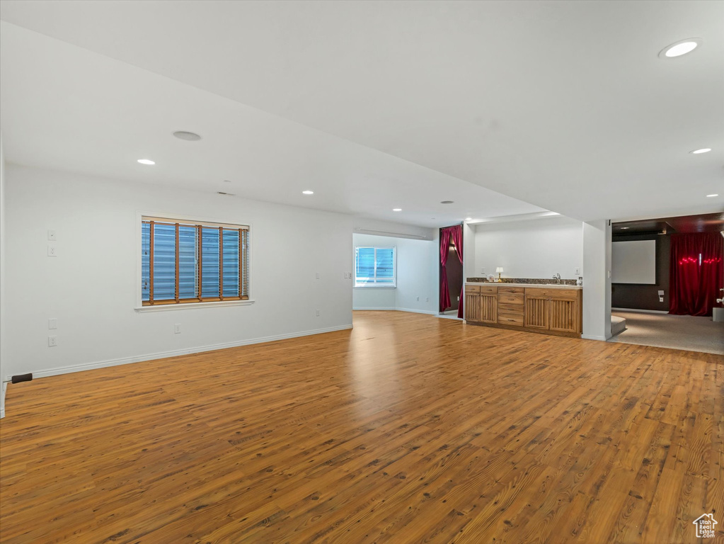 Unfurnished living room with wet bar, wood finished floors, and recessed lighting