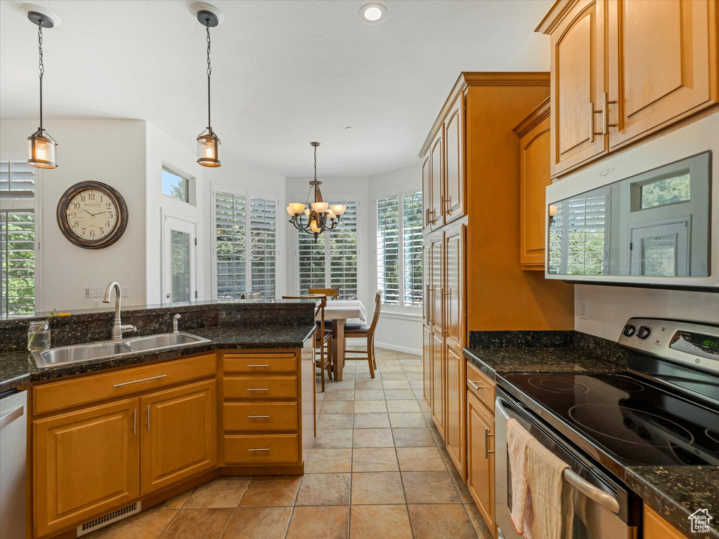 Kitchen featuring appliances with stainless steel finishes, a chandelier, hanging light fixtures, dark stone countertops, and recessed lighting