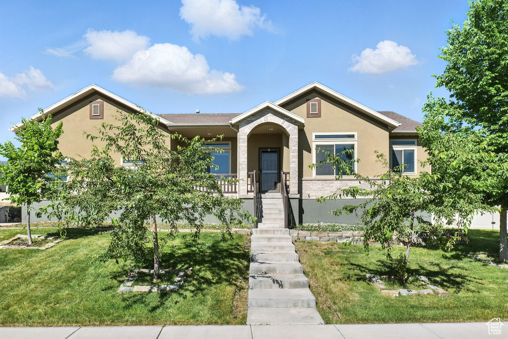 View of front of home with stucco siding, a front lawn, and stairway