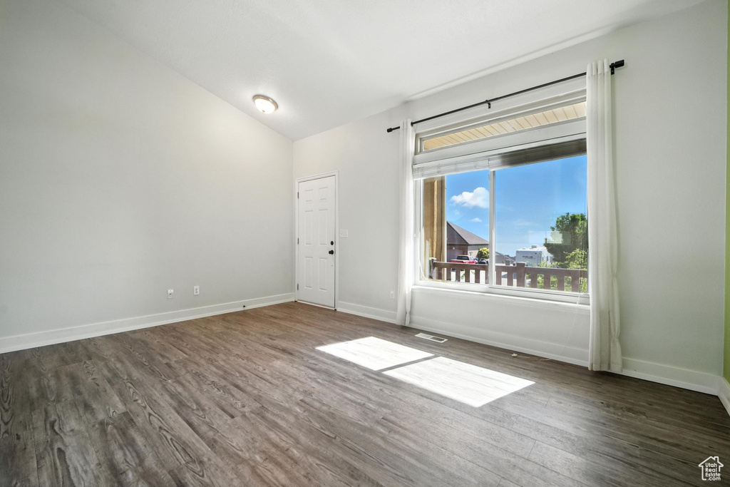 Unfurnished room with dark wood-style flooring and lofted ceiling