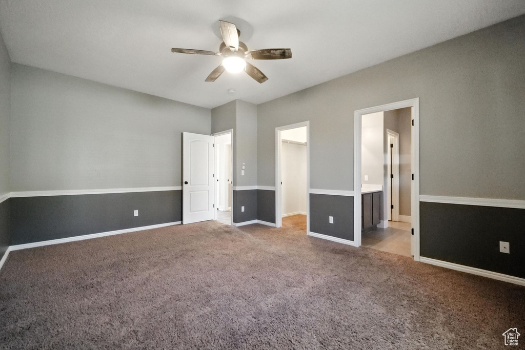 Unfurnished bedroom with carpet floors, a spacious closet, a ceiling fan, ensuite bath, and a closet