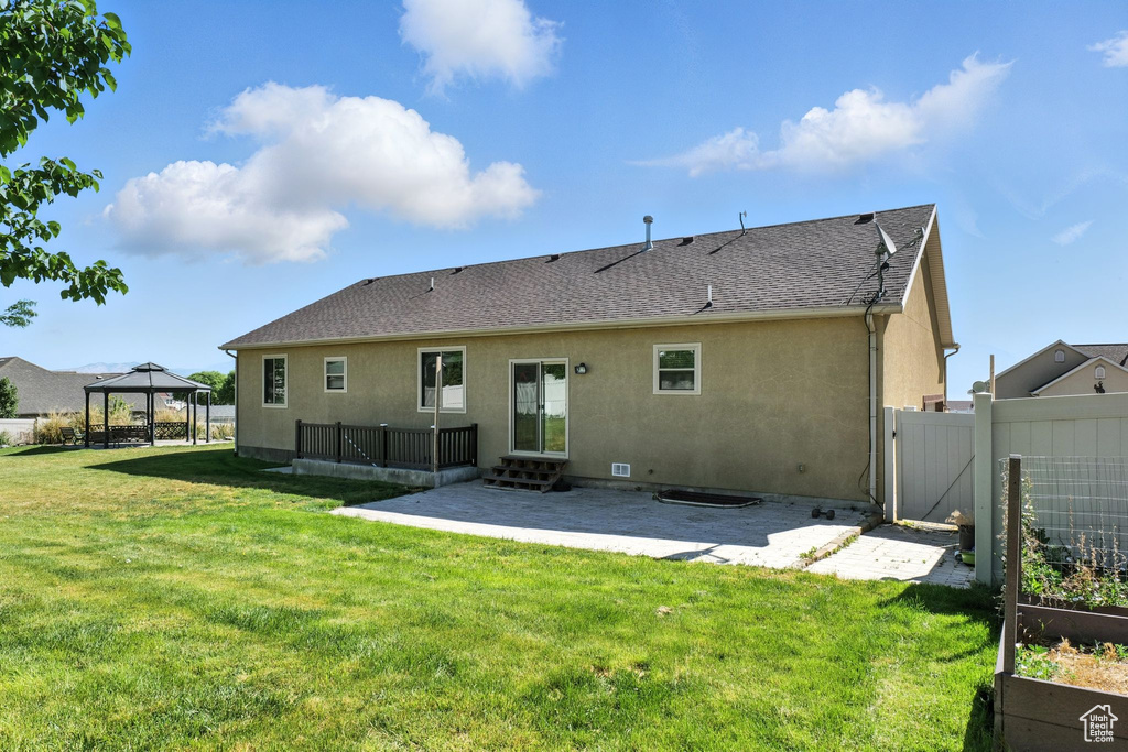Rear view of property with a patio, a gazebo, stucco siding, a garden, and a gate