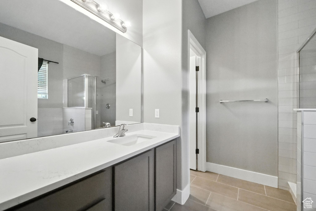 Full bathroom with tiled shower, vanity, and tile patterned flooring