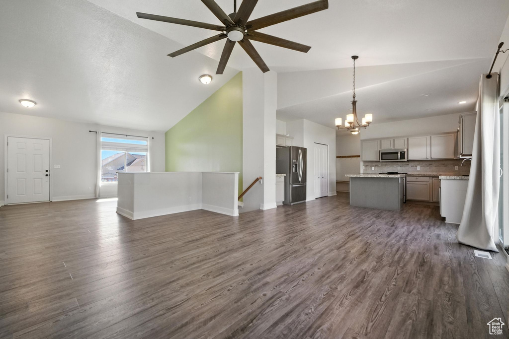 Unfurnished living room with a chandelier, a ceiling fan, dark wood-style flooring, and high vaulted ceiling