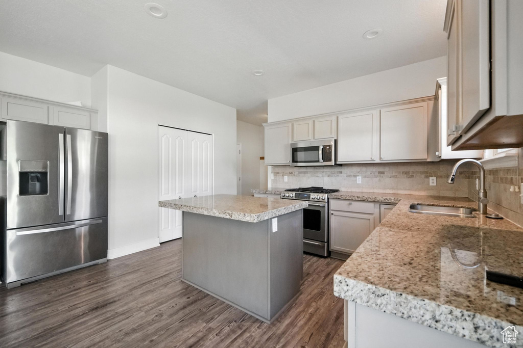 Kitchen with stainless steel appliances, dark wood-type flooring, backsplash, a kitchen island, and recessed lighting