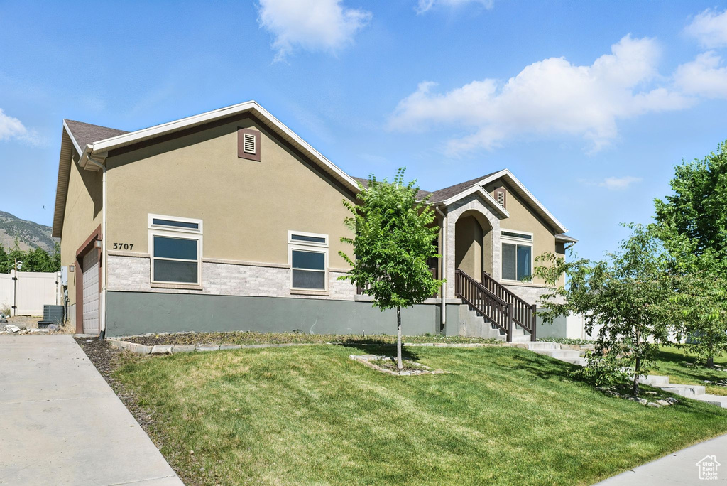 View of front of home with stucco siding, a front lawn, and driveway