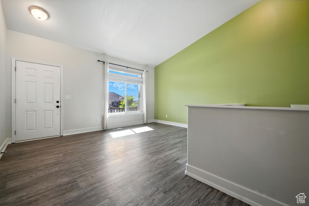 Spare room featuring dark wood-style floors and vaulted ceiling