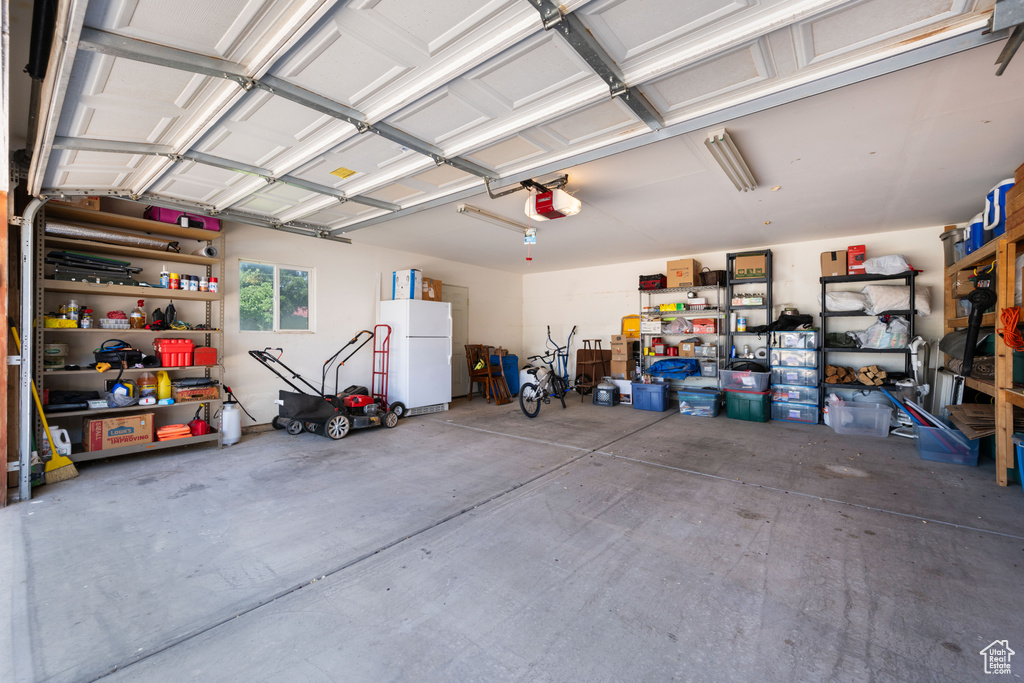 Garage with a garage door opener and freestanding refrigerator