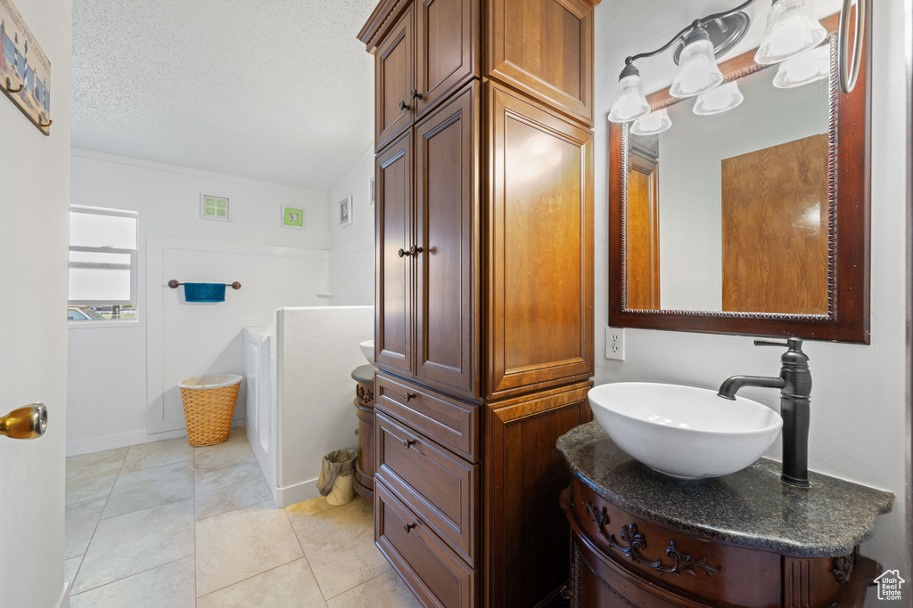 Bathroom with vanity, a textured ceiling, and tile patterned floors