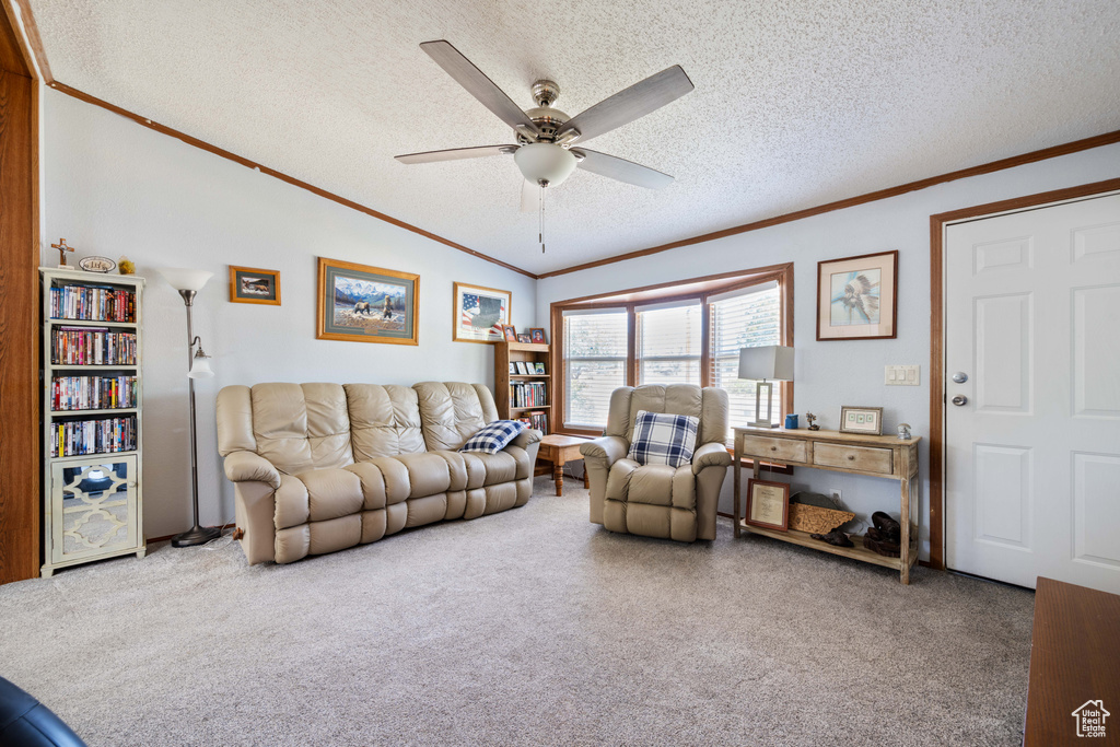 Carpeted living area featuring ornamental molding, a ceiling fan, a textured ceiling, and lofted ceiling