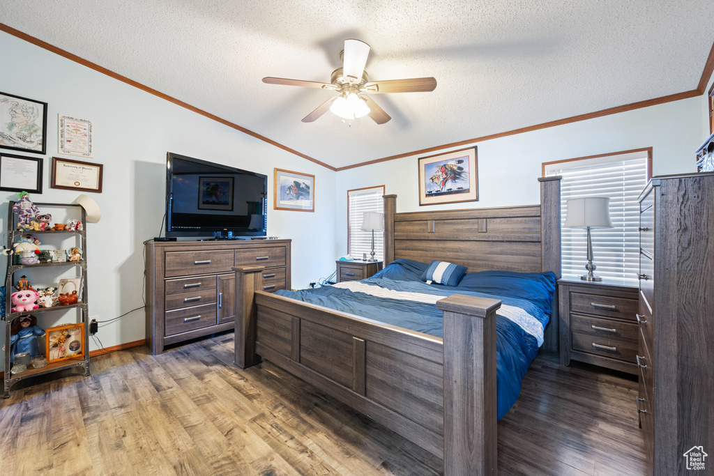 Bedroom featuring wood finished floors, a textured ceiling, ornamental molding, lofted ceiling, and a ceiling fan