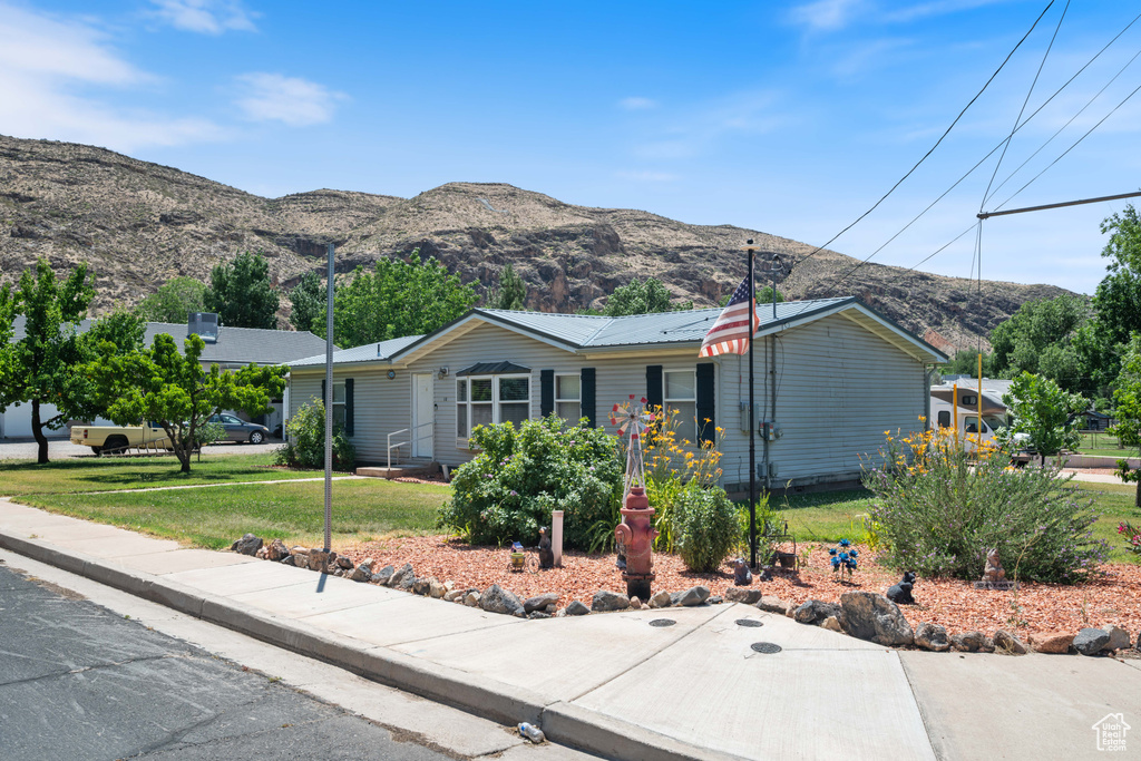 Ranch-style home with a front yard, a mountain view, and a metal roof