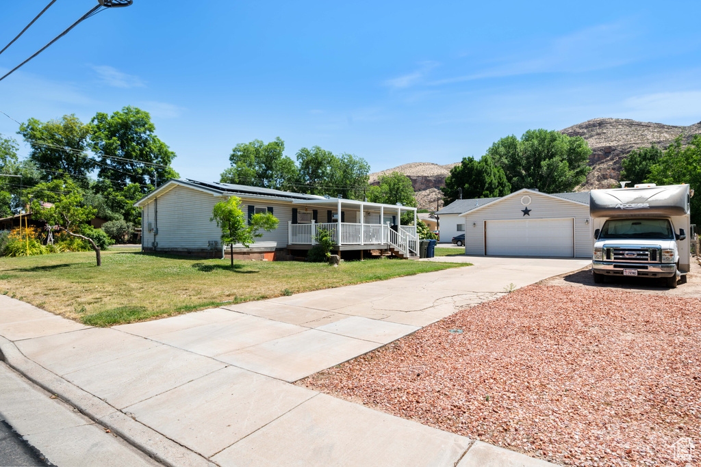 View of front of home with covered porch, a mountain view, a front lawn, driveway, and solar panels