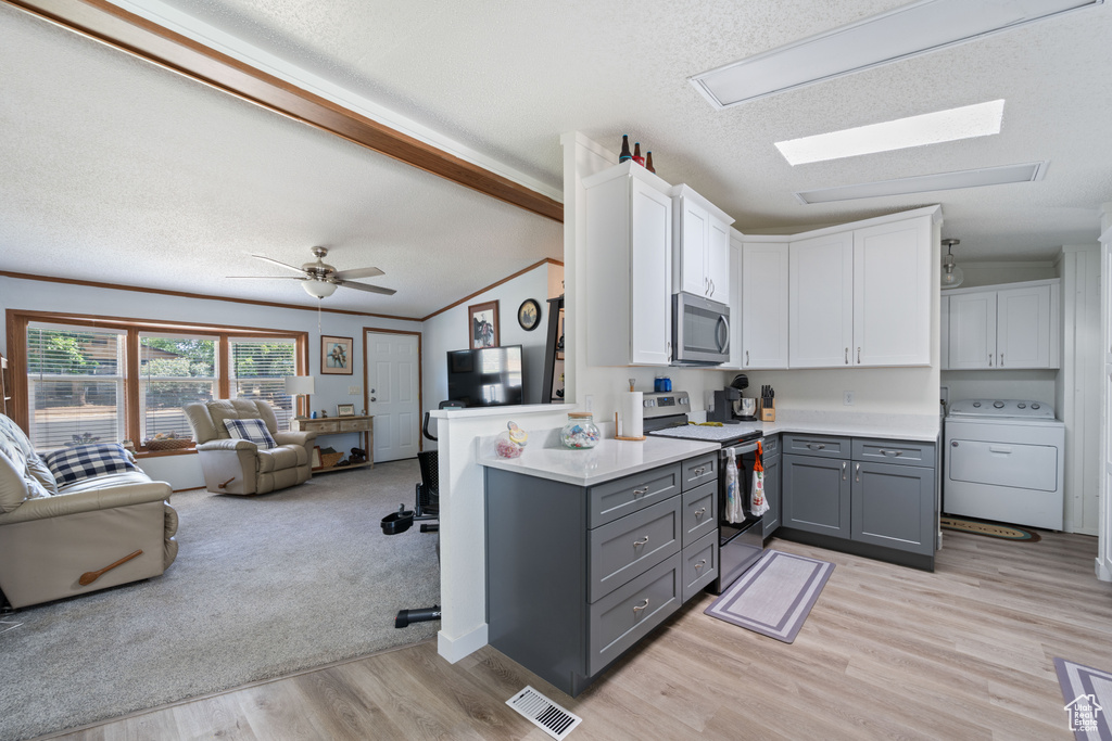 Kitchen featuring washer / dryer, gray cabinetry, stainless steel appliances, open floor plan, and white cabinets