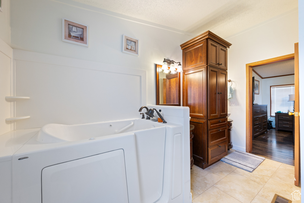 Bathroom with a garden tub, a textured ceiling, and independent washer and dryer