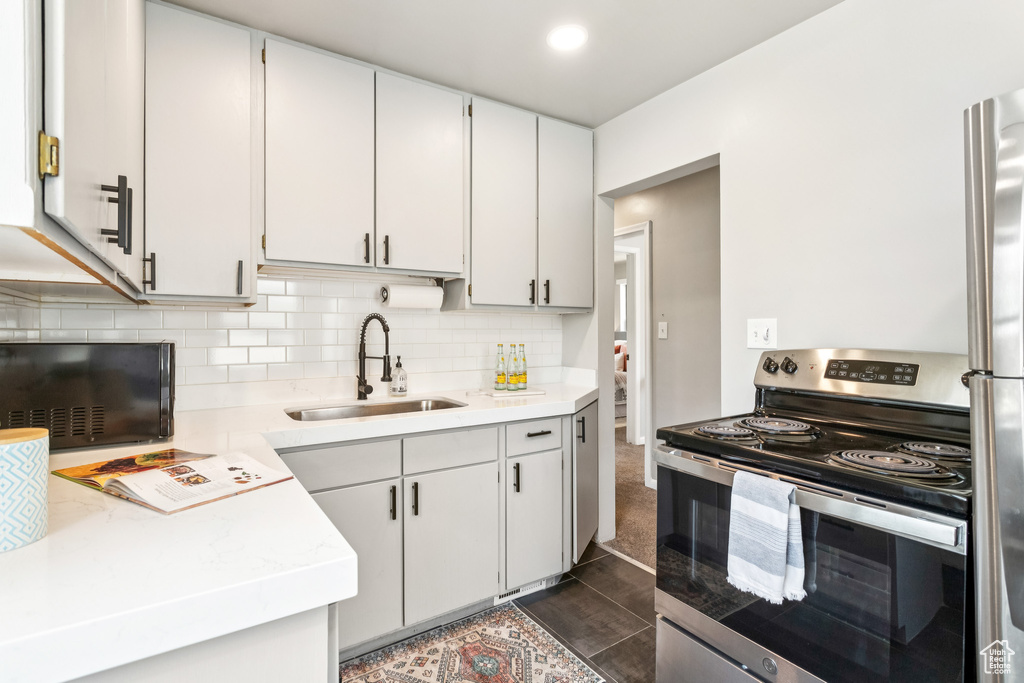 Kitchen with appliances with stainless steel finishes, backsplash, and white cabinetry