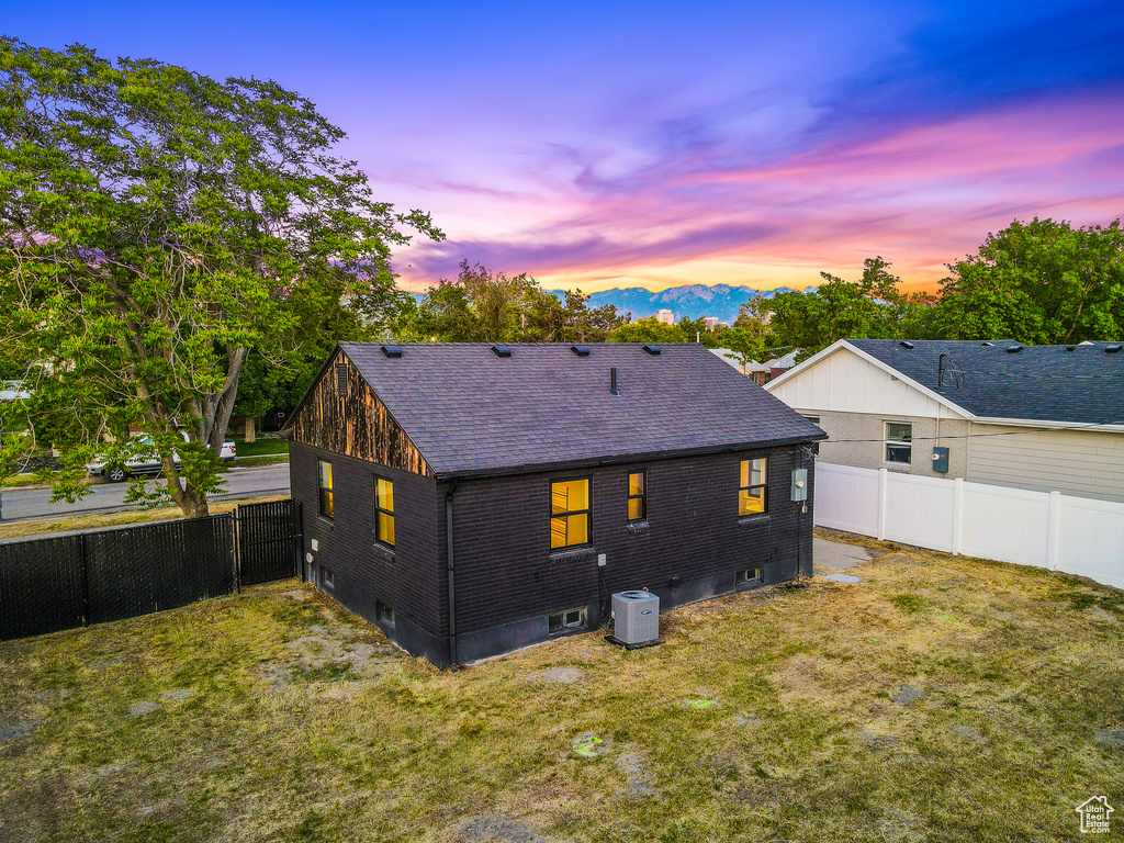 Back of house with a fenced backyard, a shingled roof, a mountain view, and brick siding