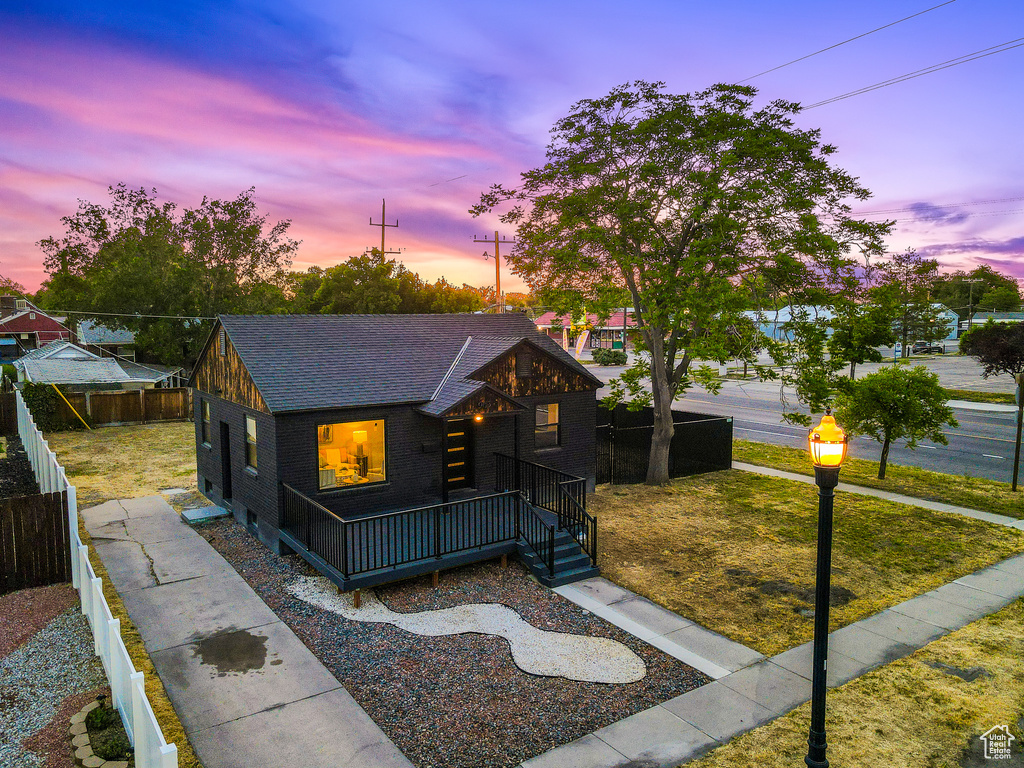 View of front of home with brick siding, roof with shingles, and a fenced backyard