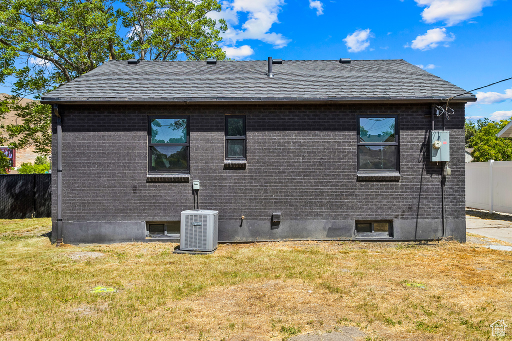 Back of property featuring a shingled roof and brick siding