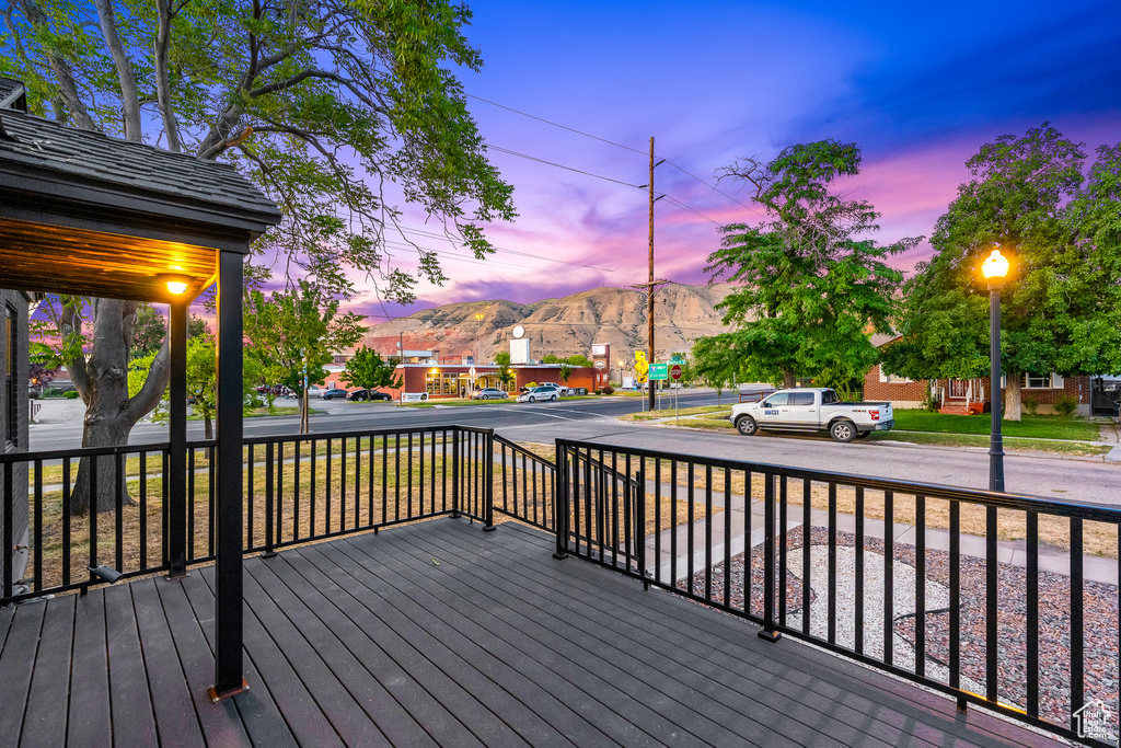 Deck at dusk featuring a mountain view and a porch