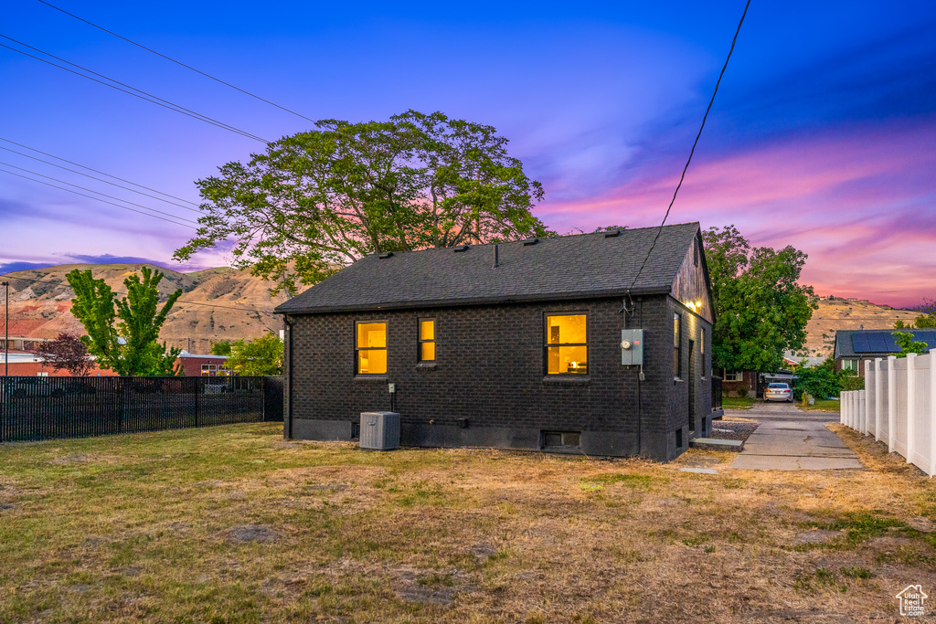 Rear view of house featuring brick siding, a fenced backyard, a mountain view, and roof with shingles