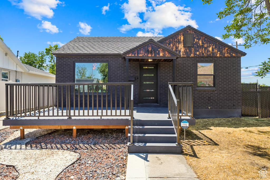 View of front facade with brick siding and a wooden deck