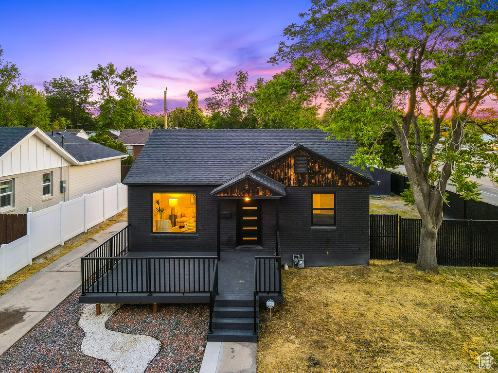 View of front of property with a shingled roof, brick siding, and a fenced backyard
