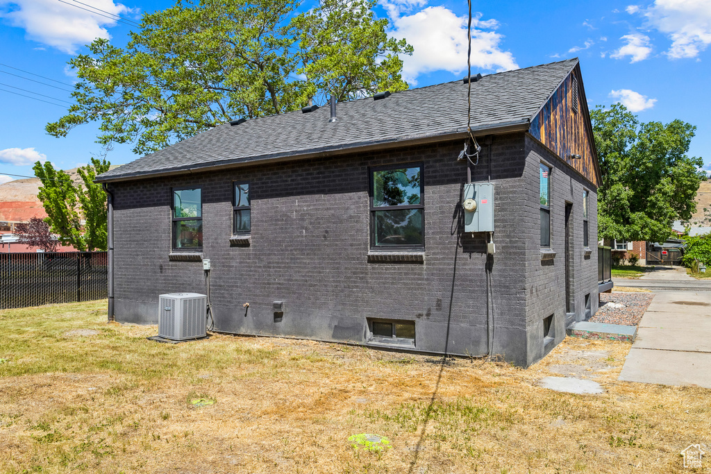 Back of house featuring roof with shingles and brick siding