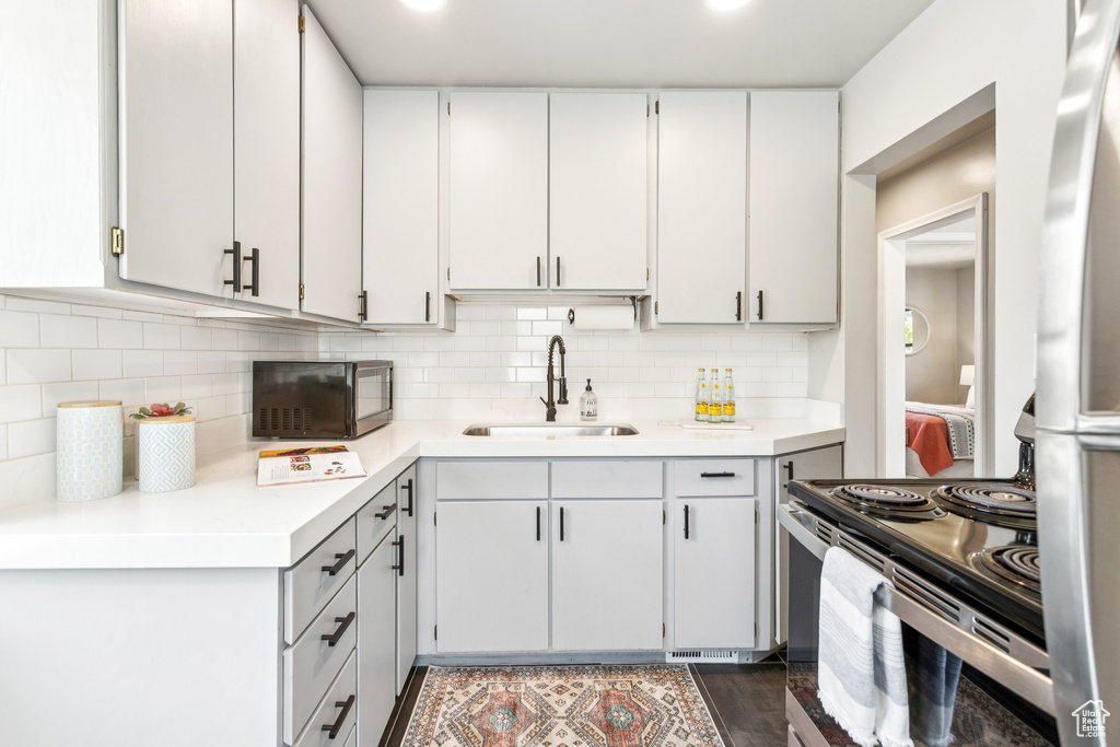 Kitchen with appliances with stainless steel finishes, light countertops, decorative backsplash, and white cabinets