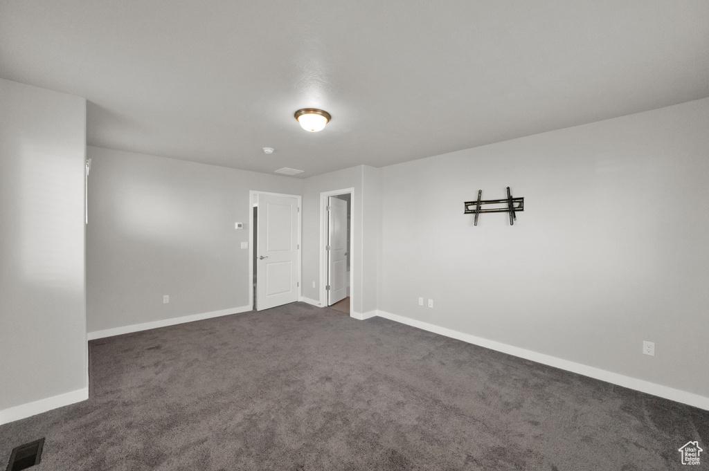 Spare room featuring baseboards and dark colored carpet