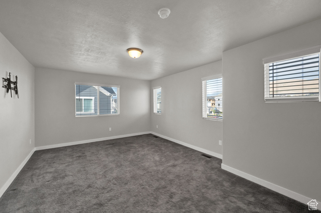 Unfurnished room with dark carpet and a smoke detector