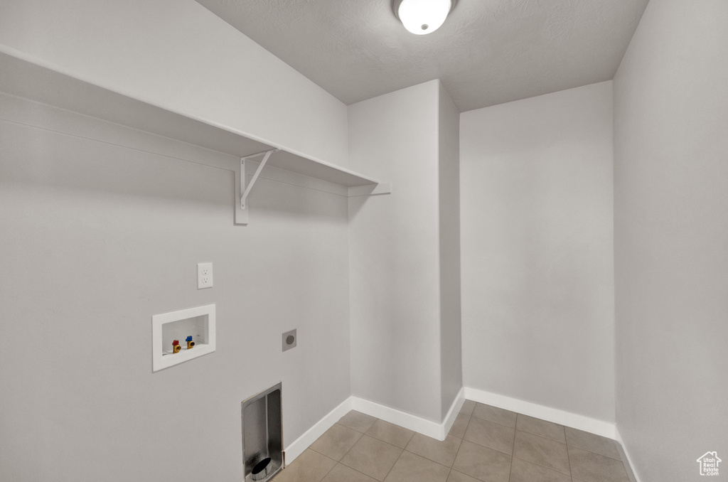 Washroom with electric dryer hookup, washer hookup, and light tile patterned floors